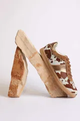 Zapatillas deportivas con estampado animal print de vaca en blanco y negro, con detalles en cuero sintético plateado en los laterales y talón.