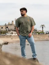 Remera Brixton oversize de algodón, color marrón con efecto acid wash, manga corta y estampa en la espalda de flores de mburucuyá con el texto vertical en color verde.