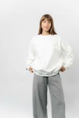 Buzo oversize de algodón frizado color beige, con cuello redondo, puños y cintura tejidos. Presenta un bordado pequeño de Snoopy en el frente.