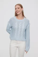 Sweater de punto color celeste, con diseño de trenzas frontales, cuello redondo y corte holgado.