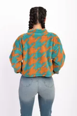 Campera corta de polar color beige con estampado de estrellas negras, cuello alto y cierre frontal.