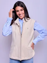 Chaleco de paño color beige, con cierre frontal, cuello alto y bolsillos laterales. Presenta un pequeño bordado distintivo en el pecho.