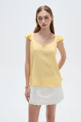 Musculosa amarilla de viscosa, con cuello en V y breteles anchos decorados con volados. Presenta un corte holgado.
