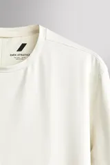 Camiseta deportiva de manga larga Zara Athleticz, de corte regular fit y color marrón topo. Confeccionada en tejido técnico elástico de secado rápido, cuenta con cuello redondo y detalle de logo estampado en el bajo.