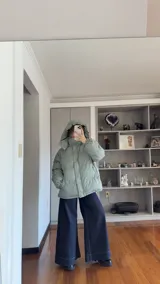 Campera puffer de corte holgado en color beige, con diseño acolchado, cuello alto y capucha desmontable. Cuenta con cierre frontal y botones a presión, además de puños elásticos.