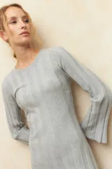 Vestido midi de punto acanalado en color gris, con mangas largas acampanadas y aberturas laterales en el ruedo. Presenta un diseño ajustado al cuerpo.