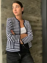 Chaqueta corta de algodón a rayas horizontales blancas y azul marino, con cuello redondo y bolsillos frontales.