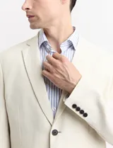 Saco de lino color beige, de corte clásico, con solapas de muesca, cierre de dos botones y bolsillos de parche.
