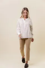 Buzo liviano de manga larga con diseño de rayas horizontales en color beige y blanco. Presenta un cuello redondo con cartera frontal de botones tipo henley, hombros caídos y calce holgado con puños acanalados.