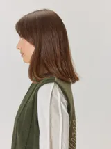 Chaleco de paño con diseño bicolor, frente en color negro y espalda en color marrón con textura de espiga. Presenta un maxi bordado de hoja en la parte posterior y detalles de tejido en los bordes.