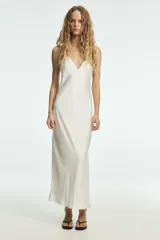 Vestido largo de satén color blanco, con cuello halter y escote en pico, de corte recto y fluido.