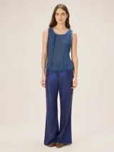 Pantalón de lino color azul metalizado, de corte sastrero, tiro medio y pierna recta amplia.