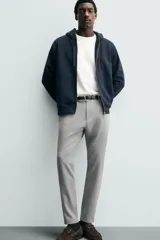 Pantalón de corte slim fit confeccionado en tejido elástico, con cintura elástica, cierre frontal con cremallera y botón, bolsillos laterales y bolsillos traseros de vivo.