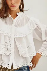 Camisa de algodón con diseño de encaje bordado, cuello mao, cierre frontal de botones y mangas largas con puños con volados.