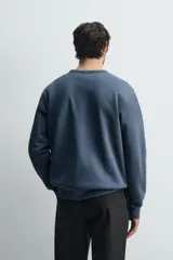 Sudadera de corte regular fit, color gris melange, con cuello redondo, manga larga y acabados en rib. Confeccionada en tejido de algodón con interior afelpado.