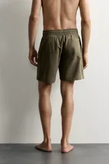 Short de baño largo en color beige, confeccionado en tejido técnico con tacto aterciopelado. Cuenta con cintura elástica ajustable con cordón, bolsillos laterales y detalle de bolsillo trasero, además de forro interior.