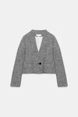 Blazer corto de tejido texturizado en blanco y negro, con escote en pico, manga larga y cierre frontal con un botón.