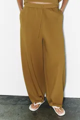 Pantalón de tiro medio y pierna ancha, confeccionado en hilatura con mezcla de algodón. Cuenta con cintura elástica con cordón de ajuste, bolsillos laterales ocultos y bajo abullonado con pliegues frontales.