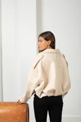 Campera de gamuza color beige, con diseño tipo globo, cuello camisero, cierre frontal y mangas amplias.