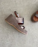 Sandalias de cuero vacuno color negro, con taco de cuña y tira ancha sobre el empeine. Ajuste con hebilla al tobillo.