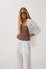 Camisa oversize blanca de manga larga con cuello camisero, bolsillo frontal en el pecho y cierre de botones.