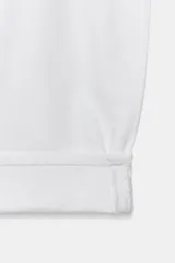 Jeans de tiro medio de corte balloon leg, color blanco, con trabillas en la cintura, diseño de cinco bolsillos, bajo con vuelta y cierre frontal con cremallera y botón.