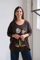 Remera de algodón color chocolate con cuello redondo, mangas largas y estampa frontal de flores en tonos plateado y dorado.