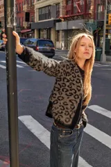 Chaqueta abierta de punto con cuello redondo y manga larga. Presenta un diseño de jacquard con estampado animal y detalles de ribetes en color negro en cuello, puños y borde frontal.