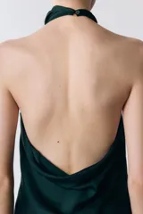 Top de cuello halter color verde oscuro, con escote drapeado, manga sisa y bajo asimétrico. Cierre en la espalda.