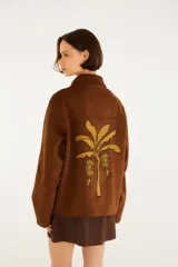 Campera de calce relajado color marrón, con cuello amplio, cierre frontal y mangas largas, confeccionada en tejido de acabado gamuzado con un parche bordado en el pecho.
