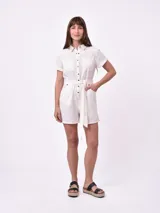Mono corto color blanco con cuello camisero, cierre frontal con botones, cinturón de lazo y bolsillos laterales.
