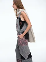 Mono de jean con diseño patchwork que combina diferentes texturas y estampados, incluyendo animal print y motivos geométricos. Presenta corte recto, bolsillos frontales y terminaciones deshilachadas.