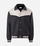 Campera de estilo varsity confeccionada en polyvelour, con diseño bicolor en gris oscuro y crema. Presenta cuello tipo polo, cierre frontal con botones a presión, mangas largas y puños y cintura con terminación en ribana a rayas.