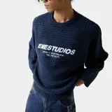 Sweater de tejido punto azul marino con textura en zigzag y corte oversize. Estampado frontal en blanco con el texto "EMESTUDIOS" y debajo "LISTEN TO YOUR FEELINGS FEEL THE YOUTH".