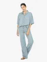 Camisa celeste de manga corta con botones en el frente y un bolsillo en el pecho.