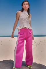 Pantalón de lino color fucsia, de tiro medio y corte holgado, con bolsillos laterales y franja vertical color crema en los laterales.