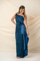 Vestido largo asimétrico de encaje color bordó, con un solo bretel y detalle de apliques florales en hombro y cintura. Presenta una pieza lateral de tafeta que cae desde el escote y un tajo pronunciado en el costado.