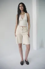 Bermuda de denim azul claro, de tiro medio y largo a la rodilla, con calce relajado y silueta amplia. Cuenta con bolsillos delanteros y traseros, y cierre frontal con botón y cremallera.