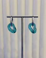 Aros colgantes compuestos por una argolla de plata 925 y un dije de vidrio soplado con forma orgánica irregular en color turquesa.