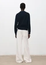 Sweater azul marino de punto, con cuello redondo y líneas blancas decorativas en las mangas raglán.