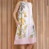 Vestido corto sin mangas, con estampado de hojas en tonos beige y verde, y falda color lila con detalle de flecos en el ruedo.