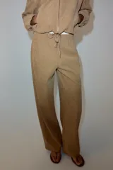 Pantalón de tiro medio color beige, de pierna ancha y corte recto. Cuenta con cintura elástica ajustable con cordones y bolsillos frontales.