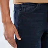 Pantalón de jean corte regular con diseño clásico de cinco bolsillos, cierre de cremallera y botón metálico.