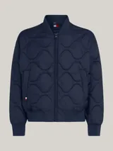 Campera bomber azul marino con diseño acolchado, cuello estilo béisbol, cierre de cremallera, dos bolsillos delanteros ribeteados, cuello, puños y bajo de punto canalé y parche con el logo de Tommy Hilfiger en la manga.