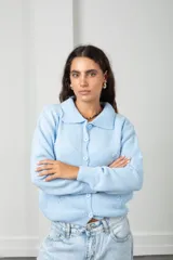 Saco tejido de punto color celeste, con cuello tipo polo, cierre frontal con botones a tono y diseño con flores bordadas en relieve. Posee mangas largas con puños acanalados y ruedo elástico.