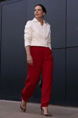 Chaqueta corta color arena con cuello camisero, cierre frontal con botones y mangas largas.