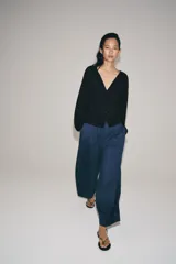 Pantalón de tiro medio con pierna ancha, confeccionado en mezcla de lyocell y viscosa. Cuenta con cintura elástica ajustable con cordones y bolsillos laterales ocultos en la costura.