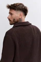 Sweater de punto acanalado en color marrón oscuro, con cuello alto y cierre frontal de cremallera parcial. Presenta mangas largas y puños ajustados.