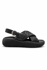 Sandalia de plataforma color negro, con tiras cruzadas en el empeine con estampado floral tono sobre tono, tira ajustable al talón con hebilla metálica dorada y suela chunky.