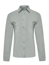 Blusa de estilo camisero color gris claro, con mangas largas, cierre frontal de botones y dos bolsillos delanteros con solapa. Presenta un diseño funcional con tecnología de protección solar.